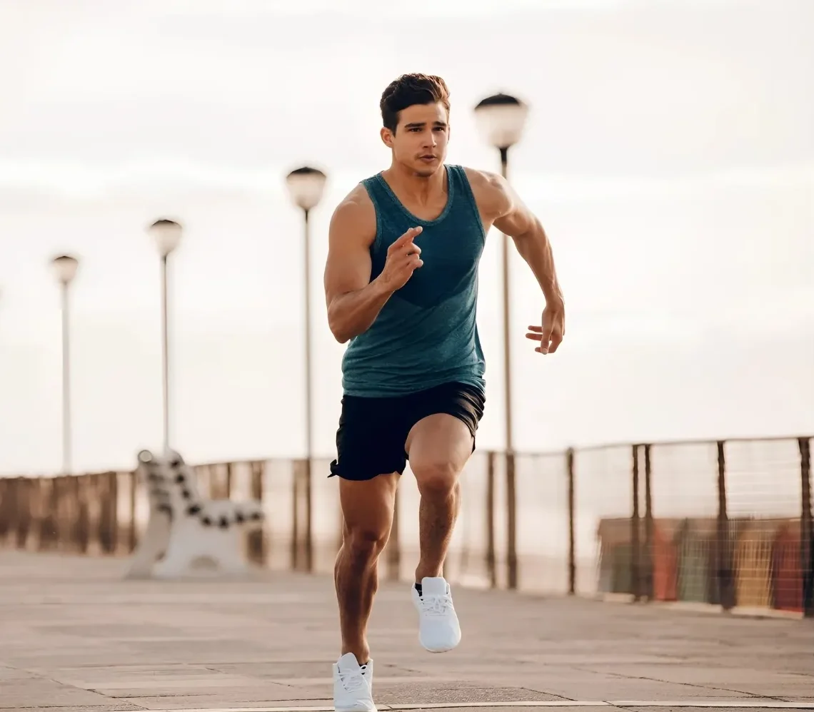 Athletic man sprinting outdoors on a promenade in sportswear.